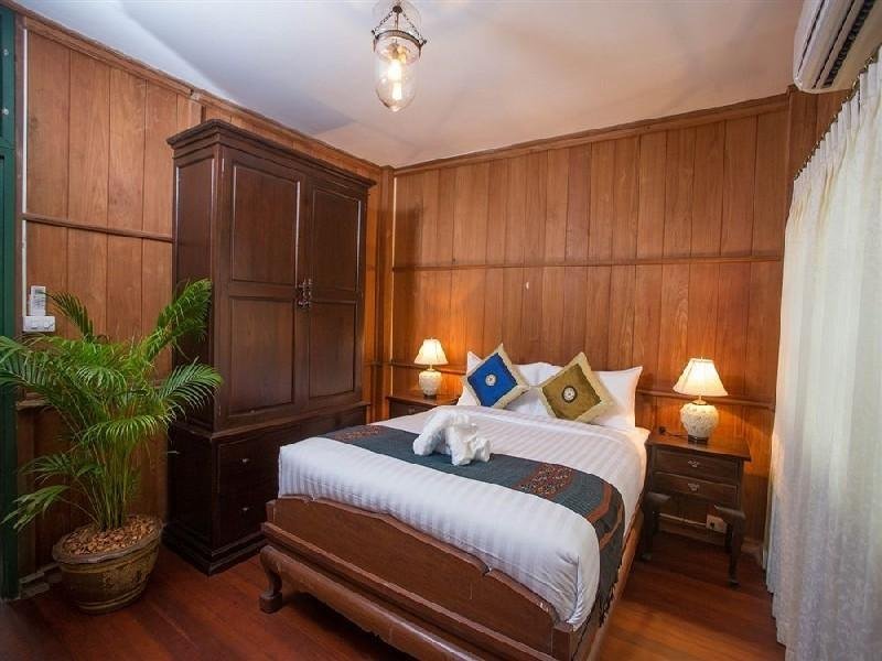 Wood-panelled double bedroom at Baan Khun Nang Colonial Residence
