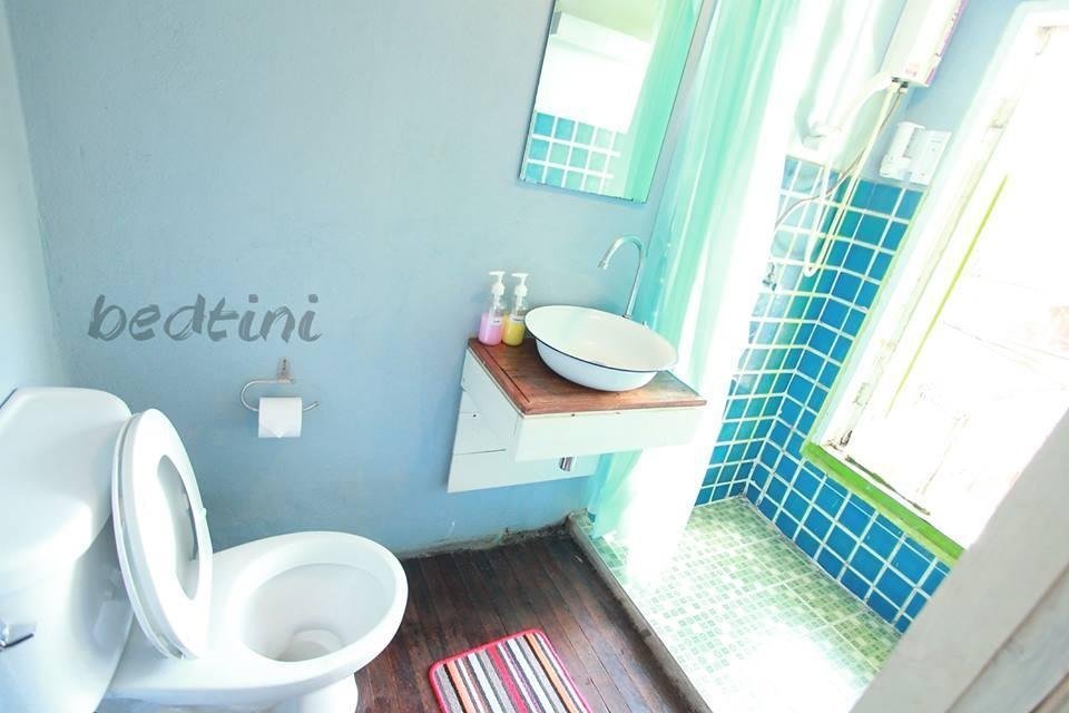 Bathroom with a basin, toilet and blue-tiled shower area at Bedtini