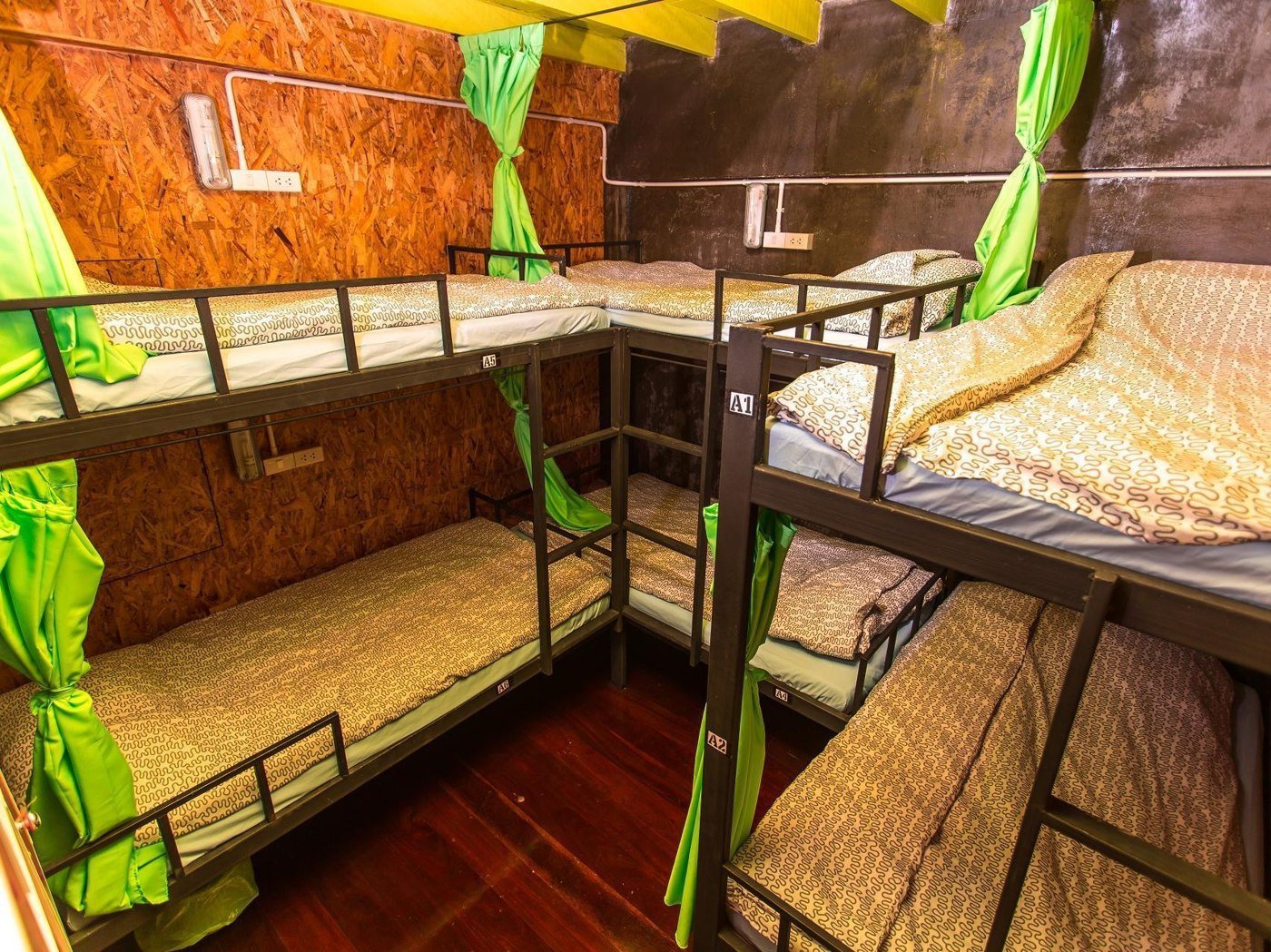 Dormitory bunks with green curtains at Hometown Hostel
