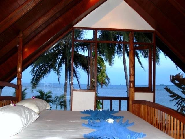 Bedroom under a pitched roof with a sea view at Laemsor Residence